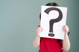 girl holding up sheet with question mark drawn on it