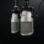 Black & white photo of two audio microphones hanging down