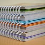 Stack of four brightly coloured spiral bound notebooks