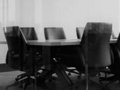 Black chairs around a wooden table in a meeting room.