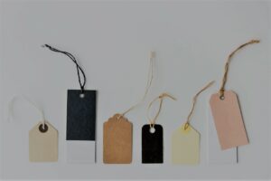 A row of assorted coloured, sized and shaped tags with strings.