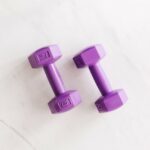 Two purple dumbbells on a white marble surface