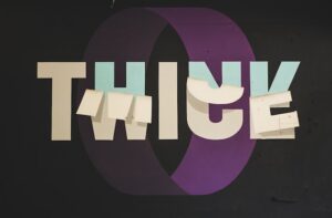 Think twice graphic art photo with the w, c and e of the word twice being partly exposed to reveal an h, n and k so it rereads as think