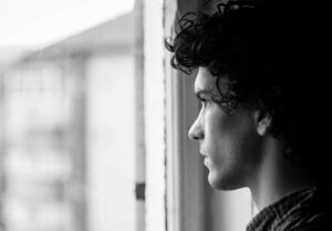 Black and white shot of young man looking out of the window