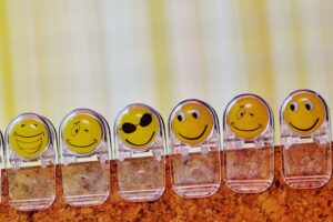 A row of clear clips with yellow heads showing various emoticon faces clipped onto a cork board